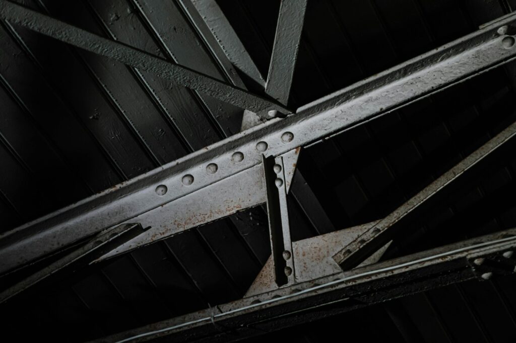 Close-up of painted, riveted steel truss members with coating wear
