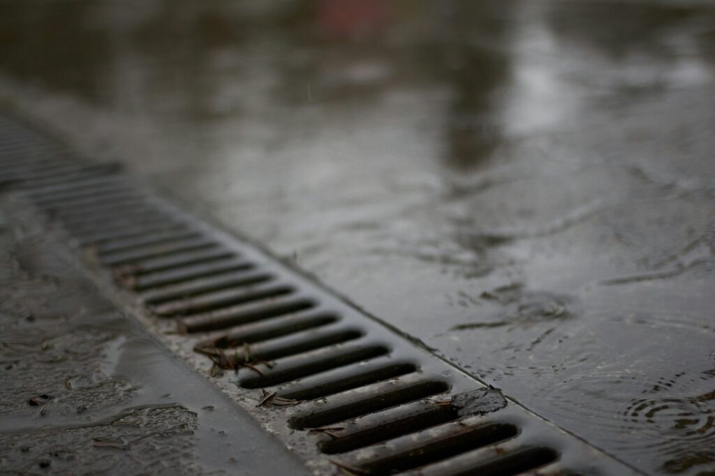 Wet concrete slab with standing water next to a channel drain