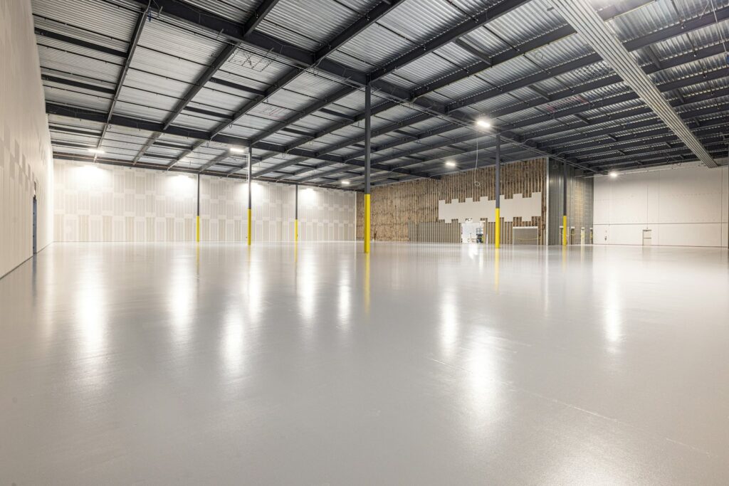 Empty warehouse with a freshly coated glossy grey concrete floor
