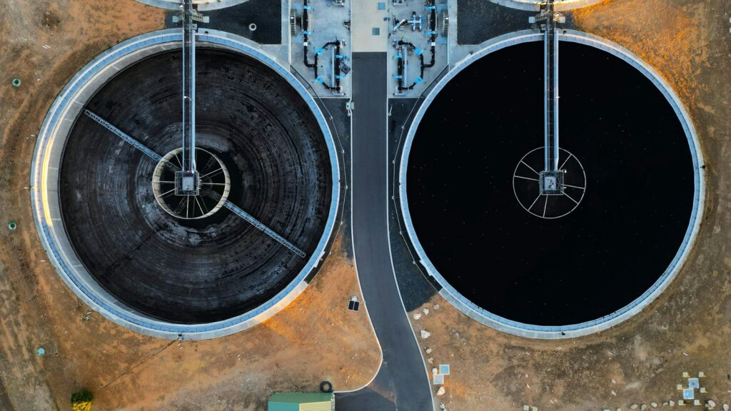 Aerial view of two circular concrete clarifier tanks at a wastewater treatment plant