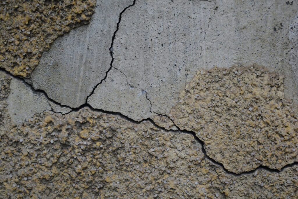 Cracked concrete surface with eroded patches of exposed aggregate